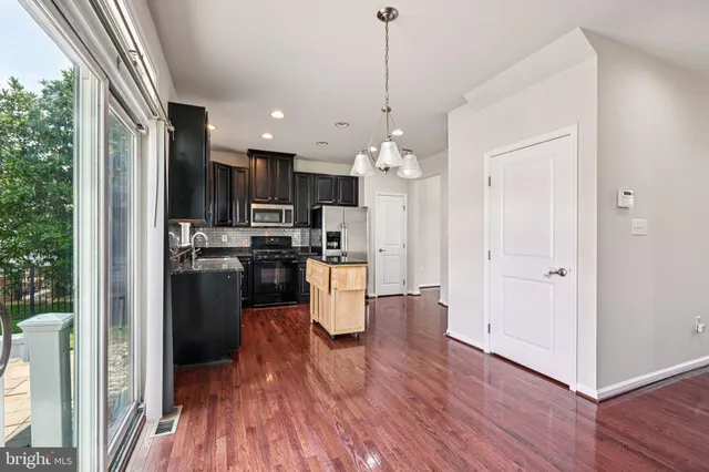 a kitchen view with stainless steel appliances a refrigerator and a wooden floor
