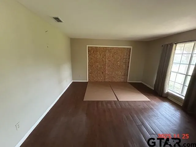 an empty room with wooden floor and windows