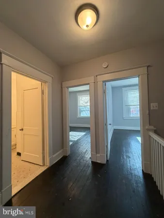 an empty room with wooden floor and windows with curtains
