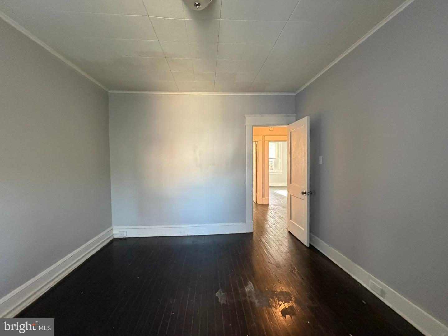 2464 Keyworth Avenue Baltimore, MD 21215 - Photo 23 of 36 an empty room with wooden floor and windows with curtains