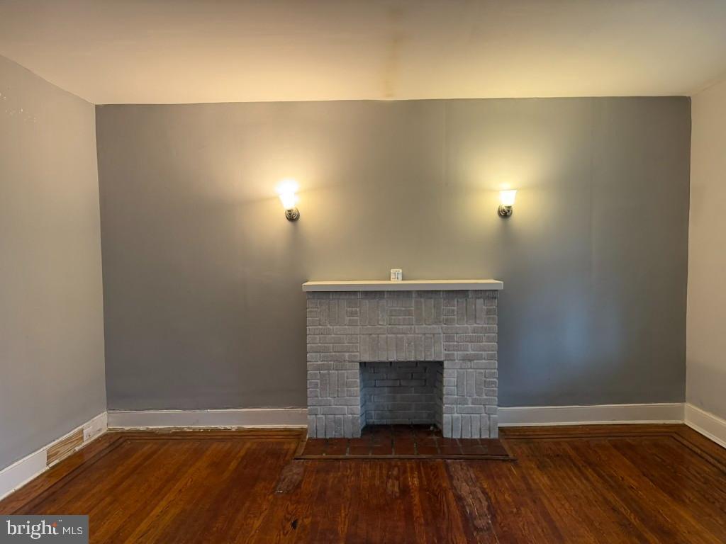 2464 Keyworth Avenue Baltimore, MD 21215 - Photo 6 of 36 an empty room with wooden floor and fireplace