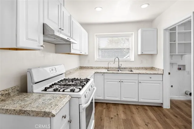 a kitchen with granite countertop a sink stove and cabinets