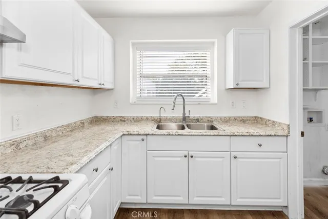 a kitchen with granite countertop white cabinets and a sink
