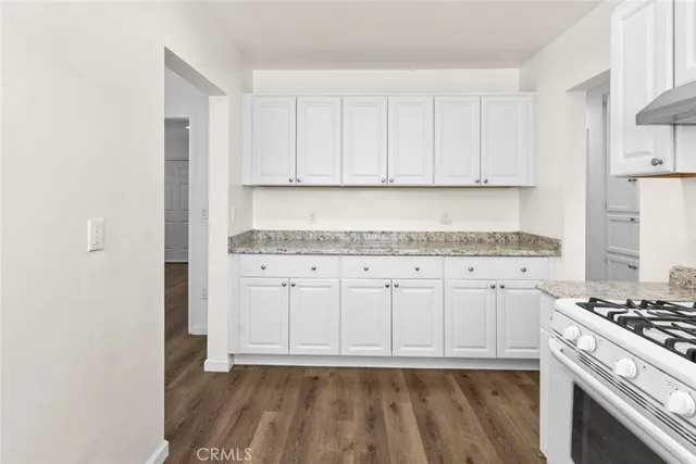a kitchen with granite countertop white cabinets and white appliances