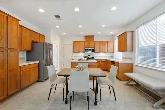 a kitchen with stainless steel appliances kitchen island granite countertop a refrigerator and a stove top oven