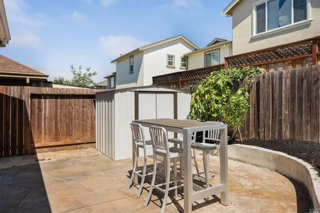 a view of a patio with table and chairs with wooden fence