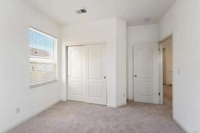 a view of an empty room with closet and a window