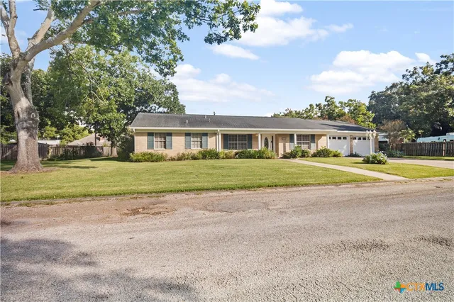 a view of a house with a big yard and large trees