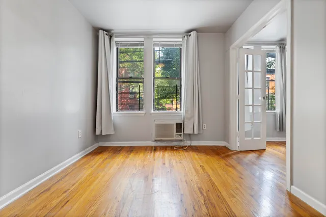 a view of empty room with wooden floor and fan