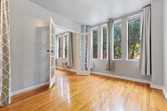 a view of an empty room with wooden floor and a window