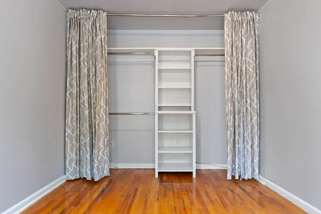 a view of empty room with wooden floor and closet