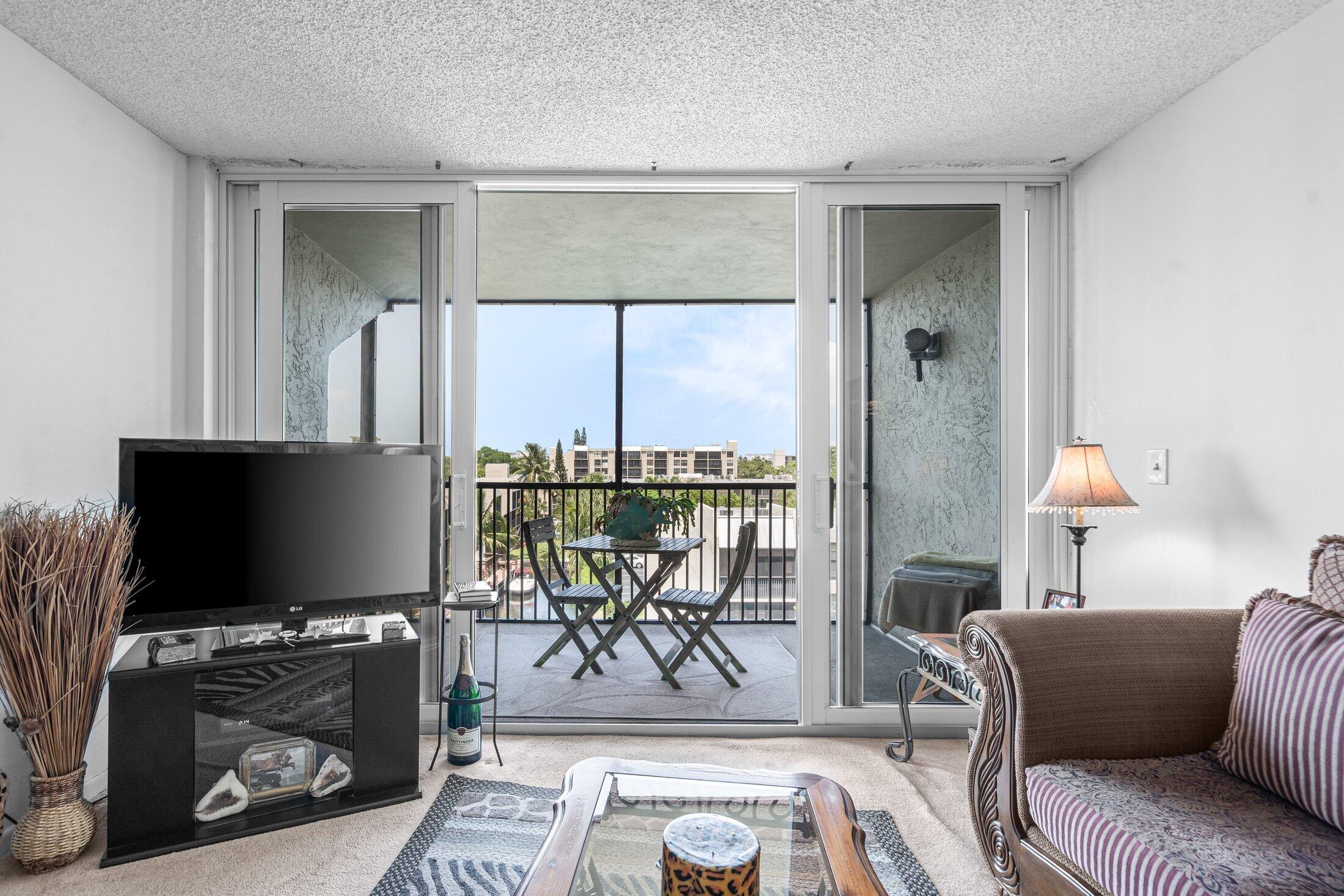 17 Royal Palm Way, Unit 504 Boca Raton, FL 33432 - Photo 16 of 44 a living room with furniture a flat screen tv and a floor to ceiling window