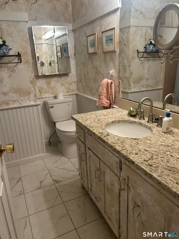 a bathroom with a granite countertop sink a toilet and mirror