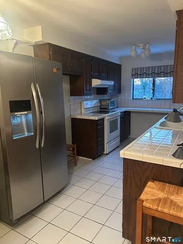 a kitchen with stainless steel appliances kitchen island granite countertop a refrigerator a stove and a sink with wooden floor