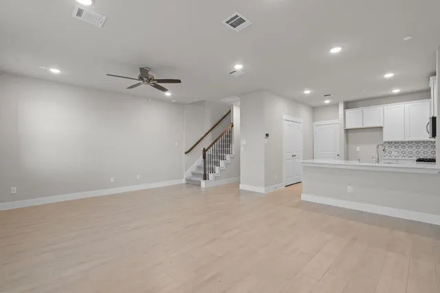 a view of an empty room with kitchen appliances and a ceiling fan