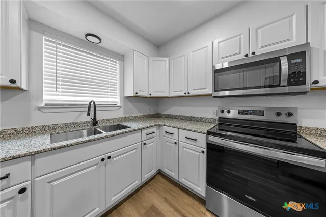 a kitchen with granite countertop cabinets stainless steel appliances and a window