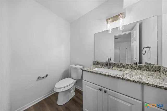 a bathroom with a granite countertop toilet a sink and a mirror