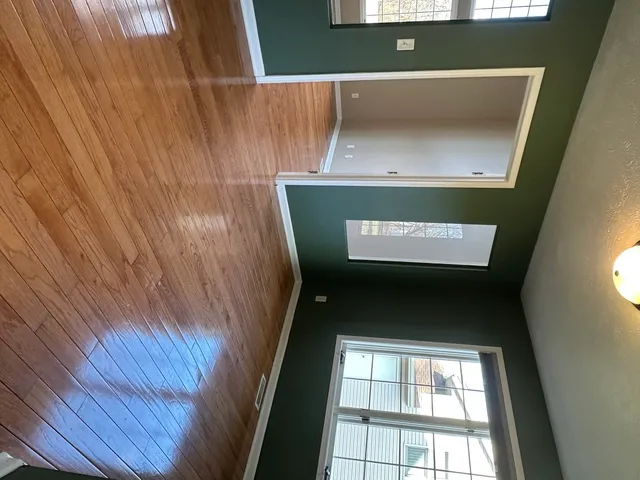 a view of a hallway with wooden floor and a window