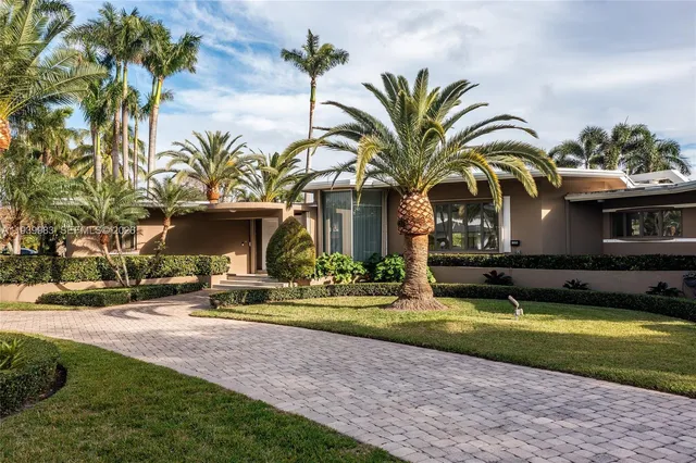 a view of a house with a yard and palm trees