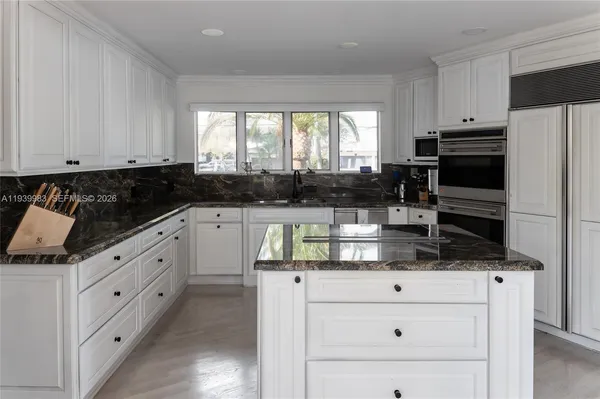 a kitchen with granite countertop white cabinets and stainless steel appliances