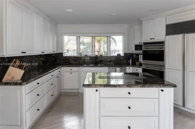 a kitchen with granite countertop white cabinets and stainless steel appliances