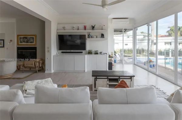 a living room with furniture a flat screen tv and floor to ceiling window