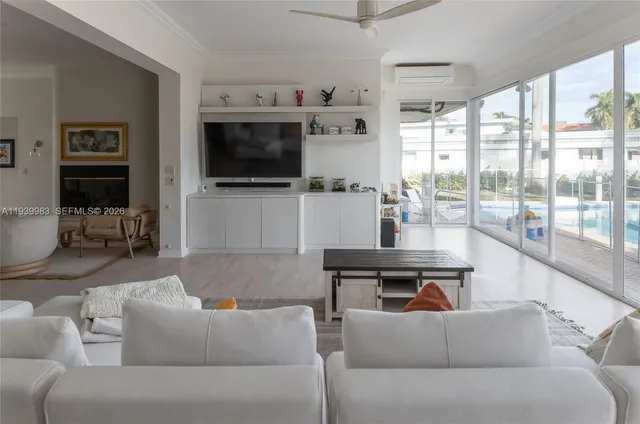 a living room with furniture a flat screen tv and floor to ceiling window