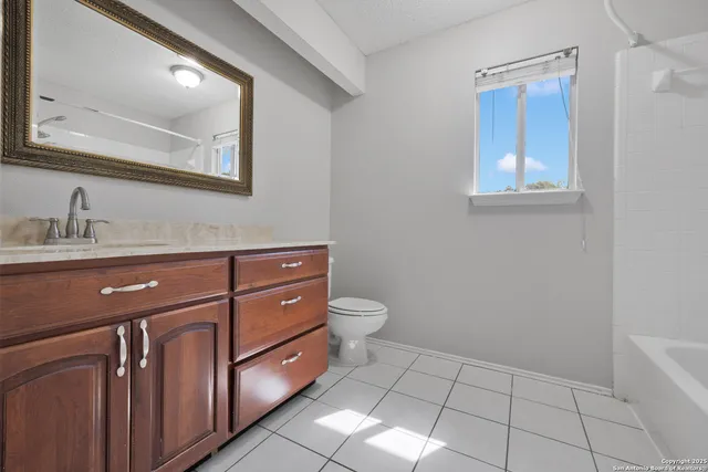 a bathroom with a granite countertop toilet a sink and mirror