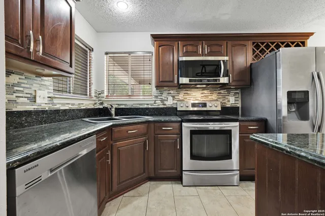 a kitchen with stainless steel appliances granite countertop a sink stove and microwave