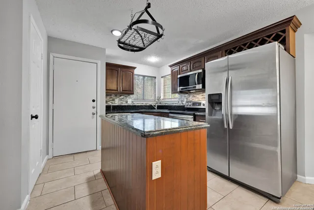 a kitchen with stainless steel appliances granite countertop a refrigerator a stove and a sink with wooden floor