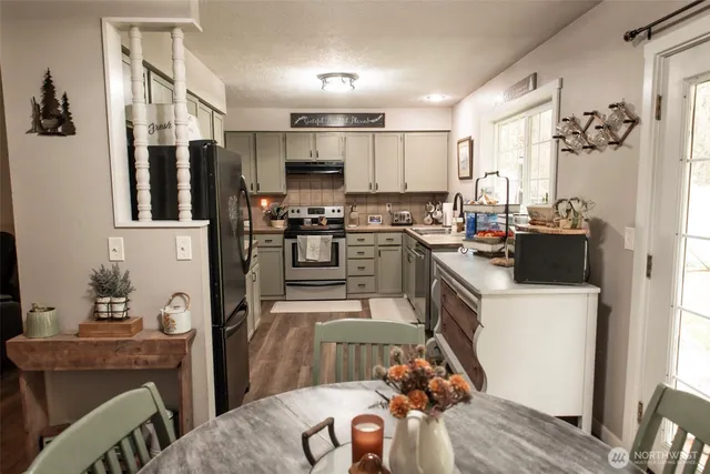 a kitchen with refrigerator a stove a sink dishwasher a dining table and chairs with wooden floor