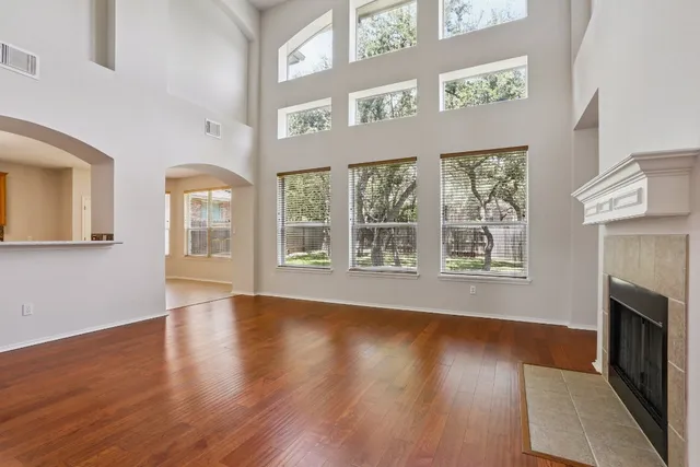 a view of an empty room with wooden floor fireplace and a window