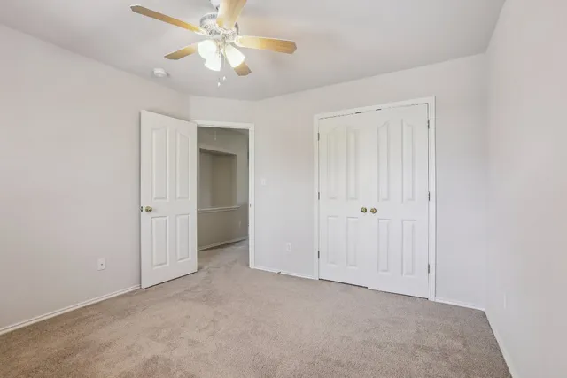 an empty room with windows and ceiling fan