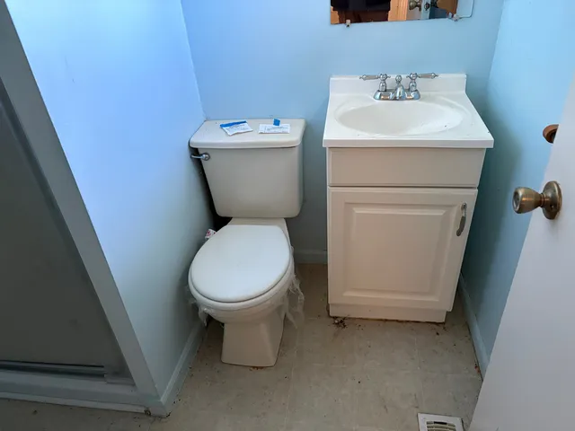 a white toilet sitting next to a white sink and vanity
