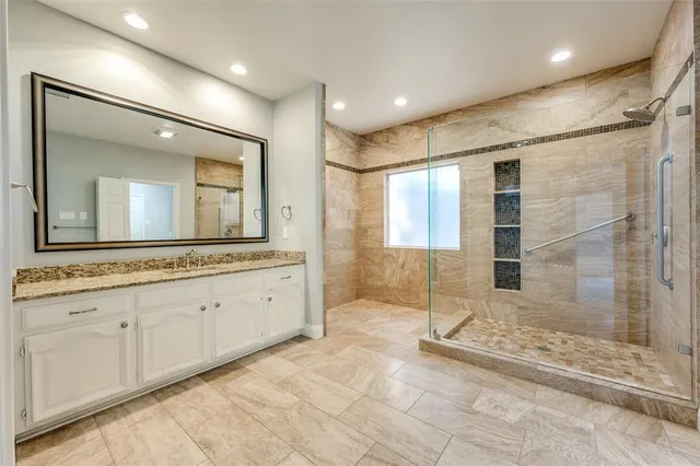 a bathroom with a granite countertop sink mirror and shower