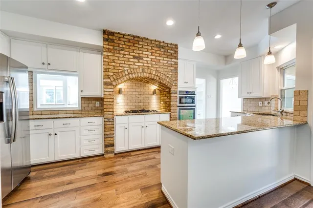 a large kitchen with granite countertop a sink window and cabinets