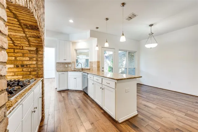 a large kitchen with granite countertop a large stove a sink dishwasher and a stove with wooden floor