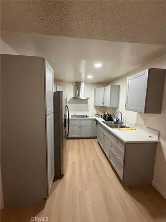 a large room with kitchen island a large counter top space a sink stainless steel appliances and cabinets