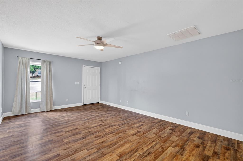 36 Bay Ridge Loop Mascotte, FL 34753 - Photo 9 of 32 a view of an empty room with wooden floor and a ceiling fan