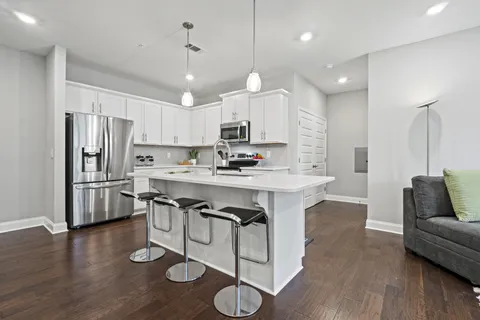a kitchen with stainless steel appliances granite countertop a refrigerator a stove a sink dishwasher a dining table and chairs with wooden floor