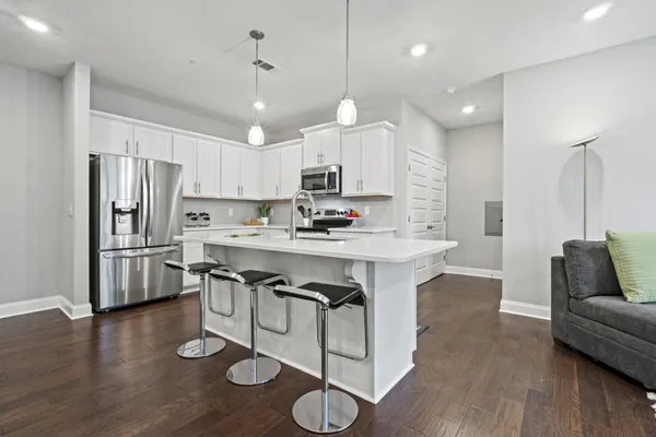 a kitchen with stainless steel appliances granite countertop a refrigerator a stove a sink dishwasher a dining table and chairs with wooden floor