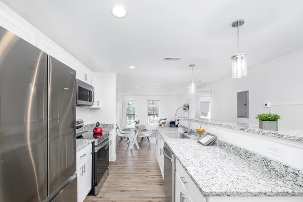 a view of a kitchen with kitchen island stainless steel appliances sink stove and refrigerator