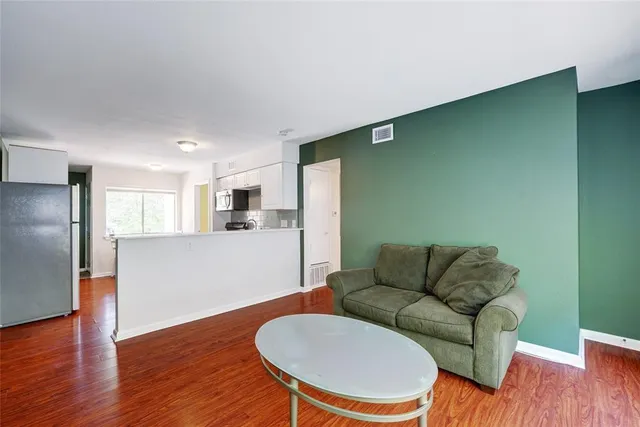 a living room with stainless steel appliances furniture and a wooden floor