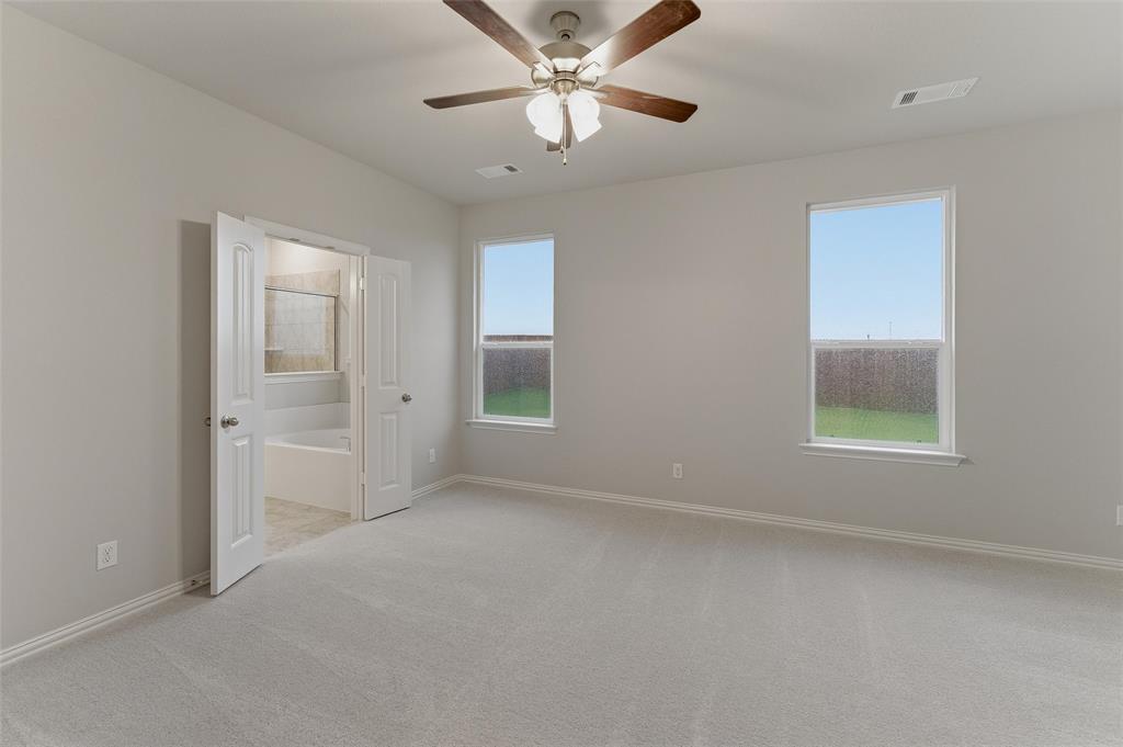 1329 Frio Drive Springtown, TX 76082 - Photo 15 of 25 Spacious room featuring light gray carpeting, two windows with white trim, and a ceiling fan with wood-finish blades