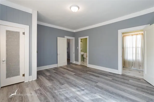 a view of an empty room with wooden floor and window