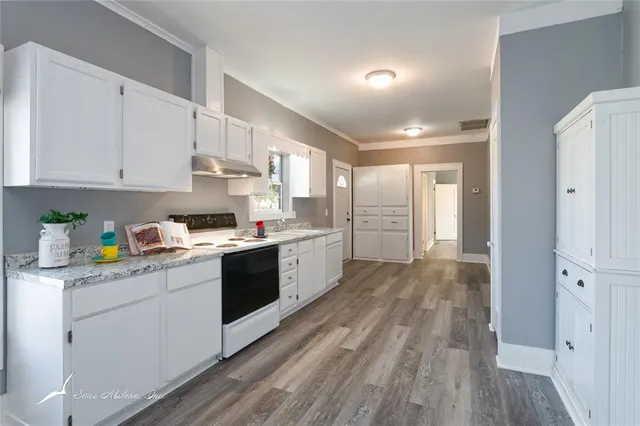 a kitchen with cabinets wooden floor and a window
