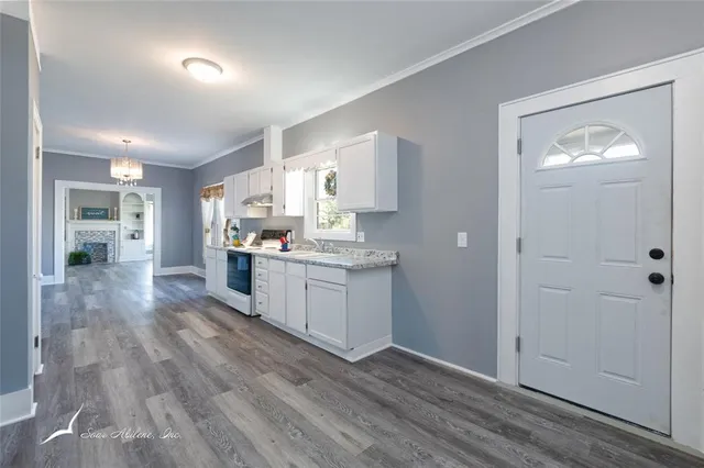 a kitchen with white cabinets and wooden floor