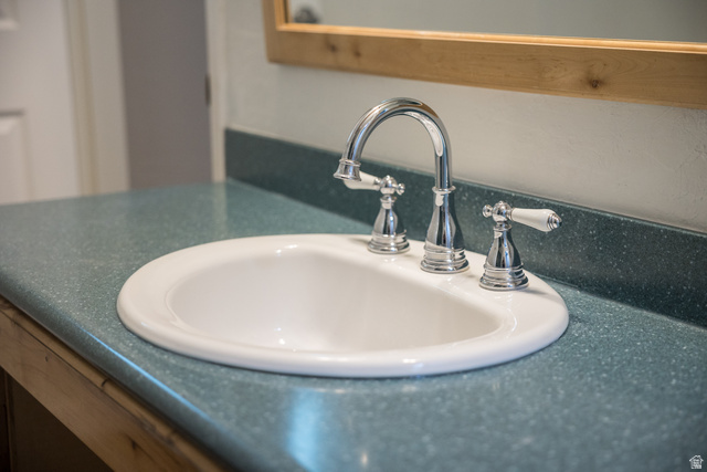 634 South 2100th Street West Vernal, UT 84078 - Photo 25 of 71 Integrated white oval sink with a chrome three-piece faucet set featuring white porcelain handles, set into a speckled turquoise countertop with a matching backsplash