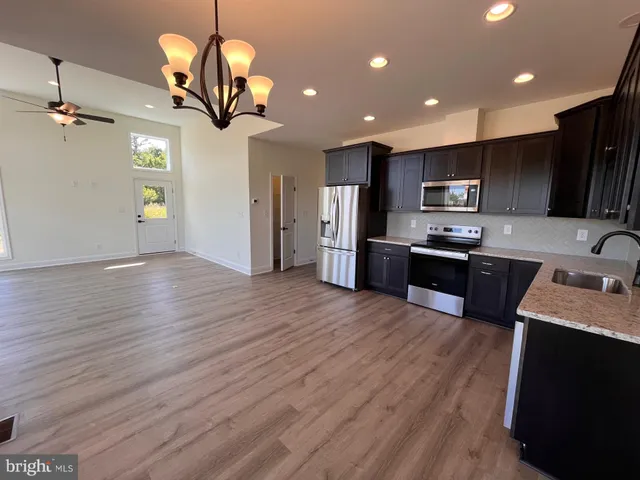 a kitchen with stainless steel appliances granite countertop wooden floors a stove and a sink