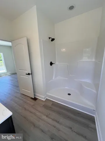 an empty room with wooden floor and a ceiling fan